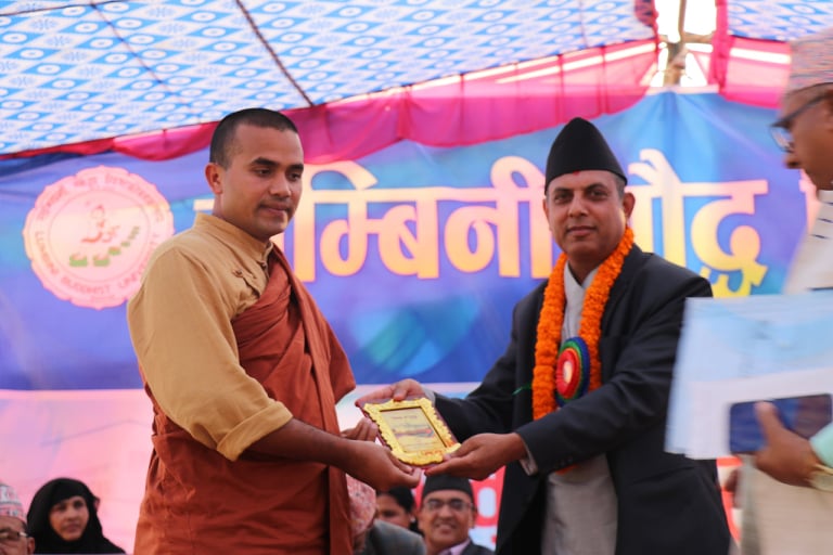 Award presentation to Dr. Tilak Ram Acharya by Buddhist monk at LBU anniversary event