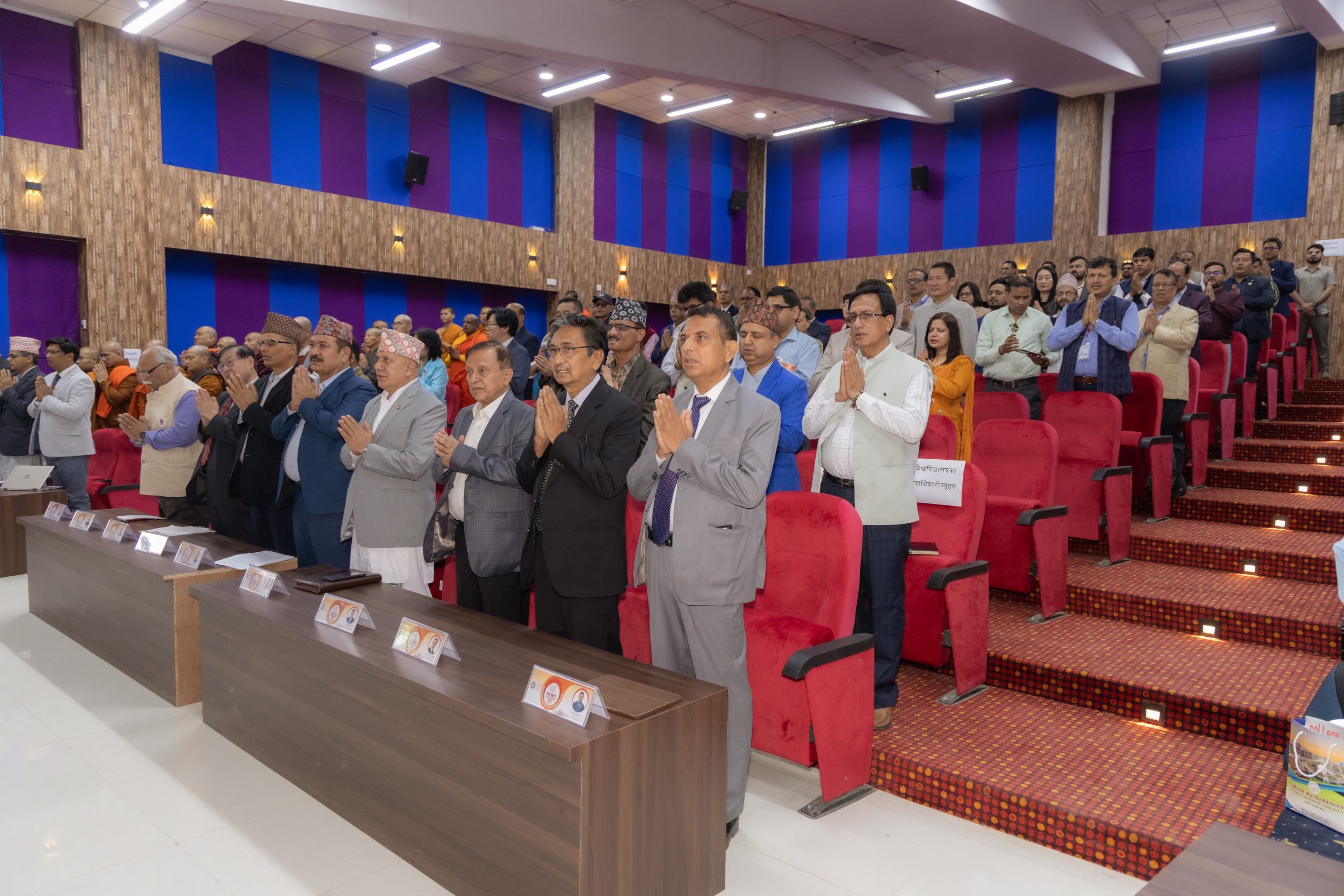 Faculty and guests offering namaste prayer at Lumbini Buddhist University ceremony hall